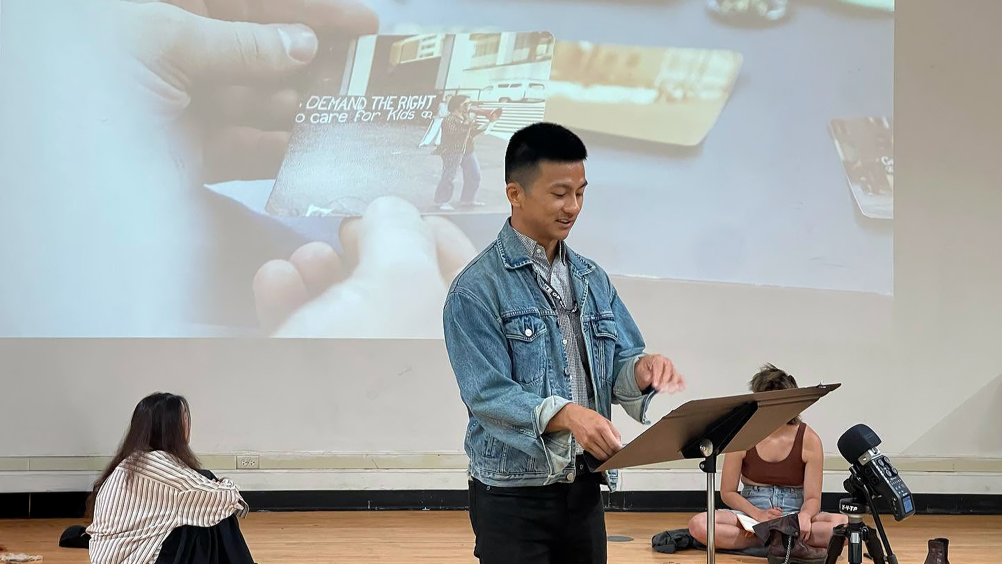 Zihan presenting at a lectern with an archival image projected behind him, Abandoned Practices 2023.